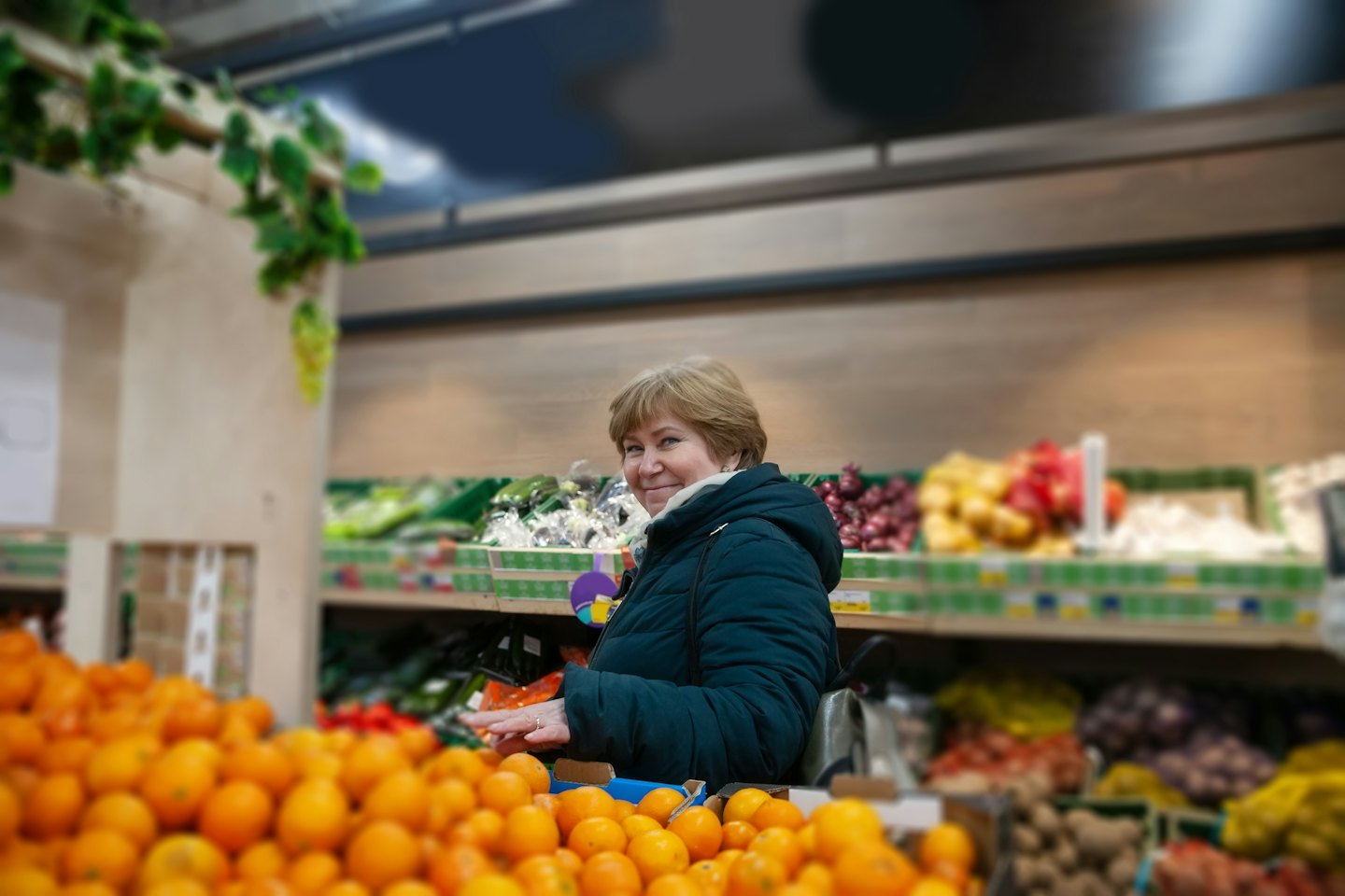 Lächelnde Frau wählt Orangen im Supermarkt aus.