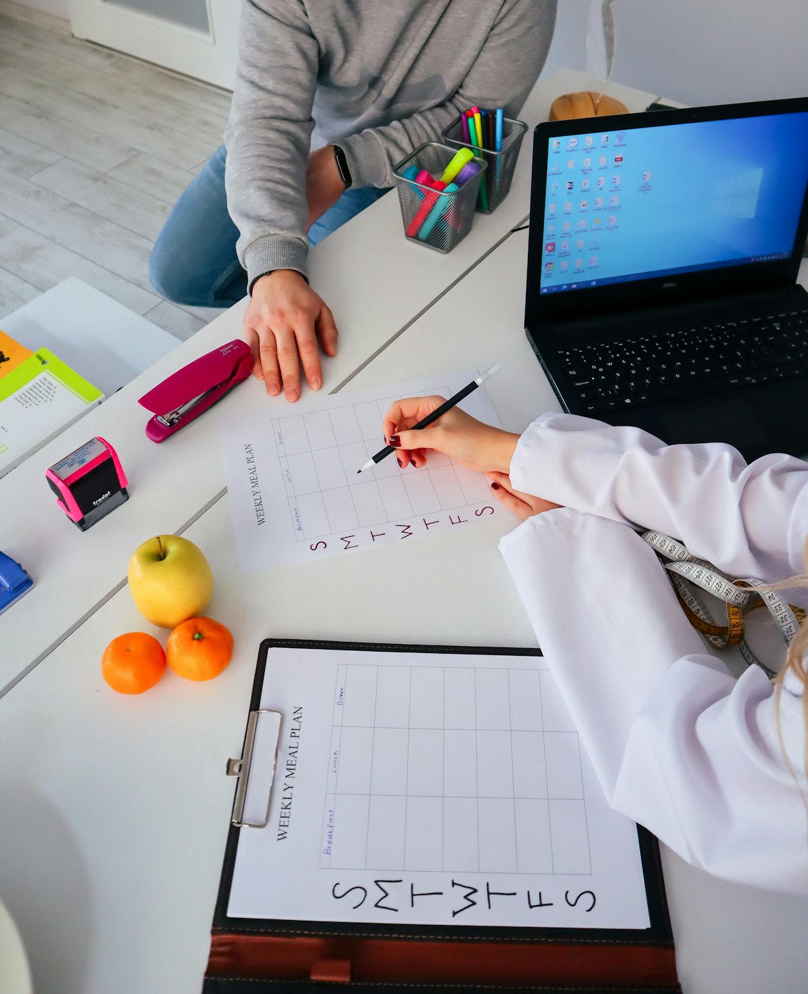 Professioneller Berater bespricht mit Klient Wochen-Speiseplan am Schreibtisch.