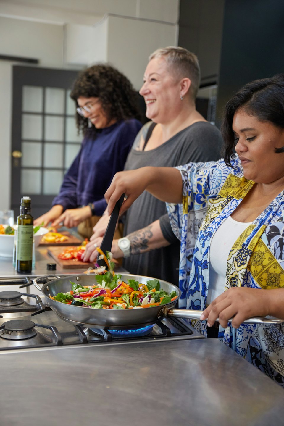 Drei Frauen bereiten gemeinsam Essen in einer modernen Küche zu.