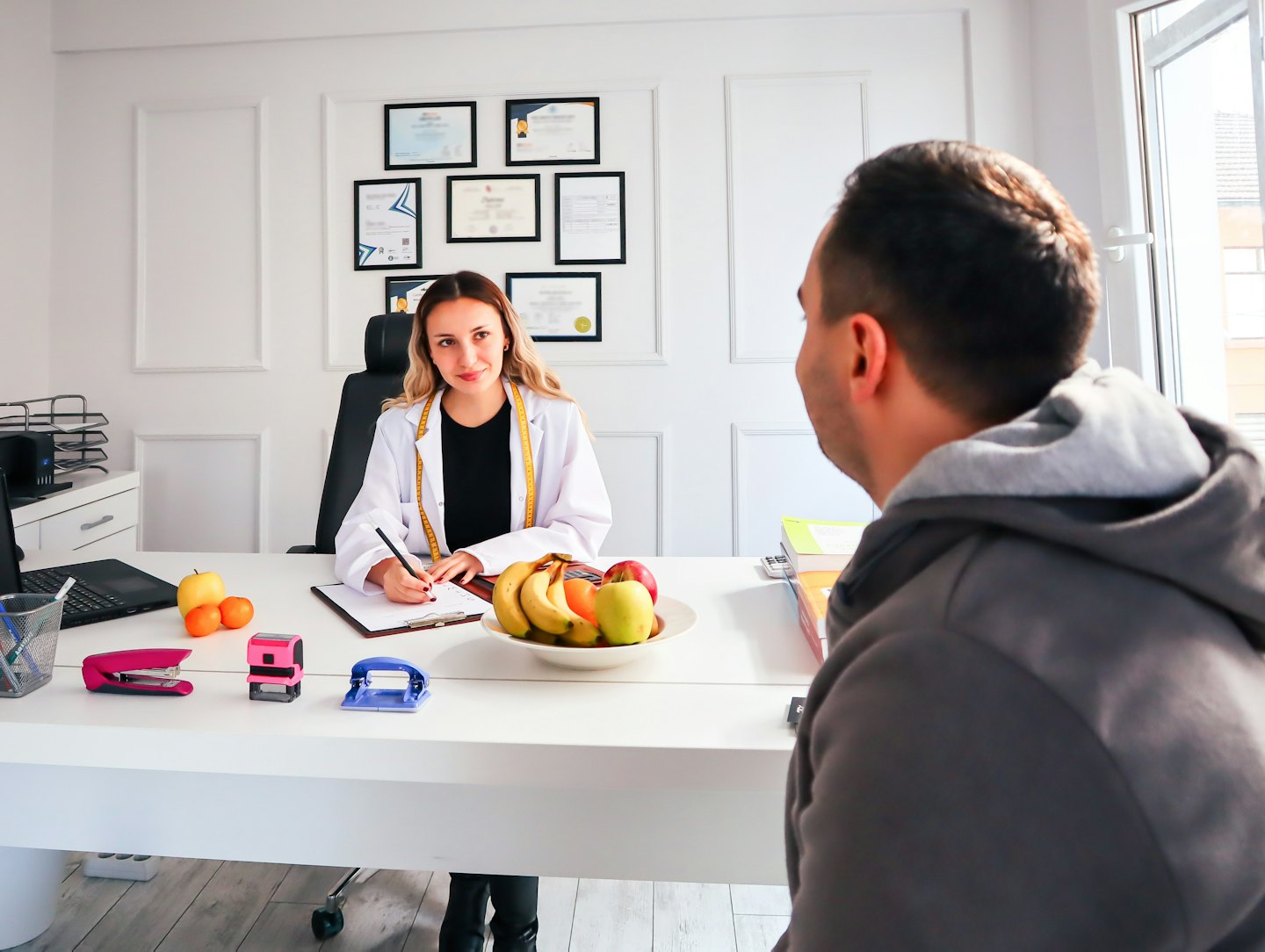 Ernährungsberaterin bespricht mit Klientin am Schreibtisch einen Gesundheitsplan.